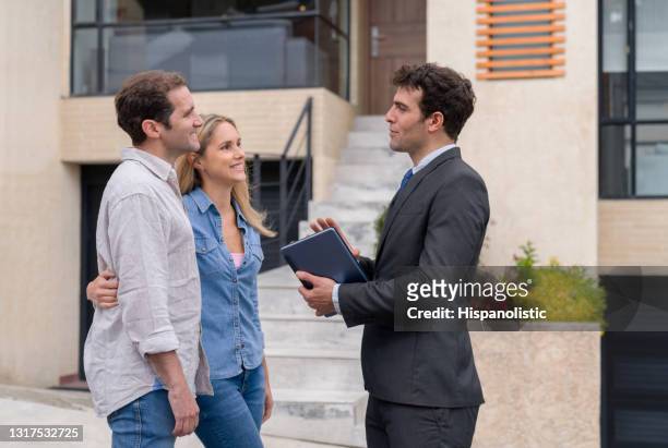 happy door to door salesperson talking to a couple outside their house - door to door salesperson stock pictures, royalty-free photos & images