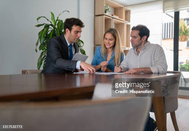 couple in a meeting with their real estate agent and signing documents - car insurance agent stock pictures, royalty-free photos & images