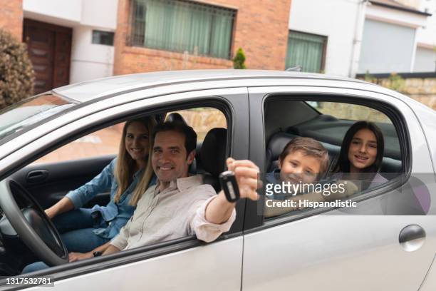familia feliz va a un viaje por carretera después de comprar un coche y sostener las llaves - autos usados fotografías e imágenes de stock
