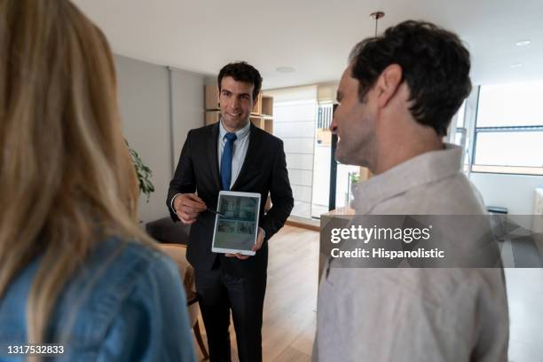 real estate agent showing a house to a couple and using a tablet computer - showing tablet stock pictures, royalty-free photos & images