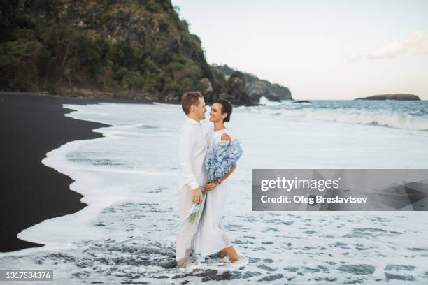 wedding couple enjoying on beach in bali. young and happy. tropical destination wedding - ranunculus wedding bouquet stock pictures, royalty-free photos & images
