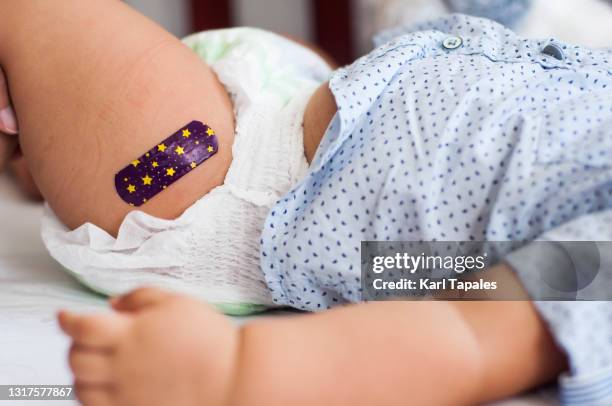 close-up view of southeast asian baby boy with medical plaster after vaccination - pleister bouwmateriaal stockfoto's en -beelden