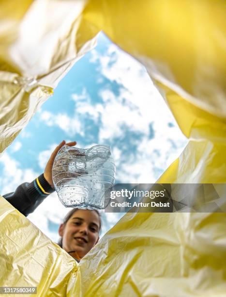 girl recycling single use plastic bottle with creative view from inside the bin. - initiative foto e immagini stock