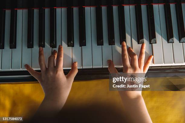 overhead view of a young child playing the piano - pianist fotografías e imágenes de stock