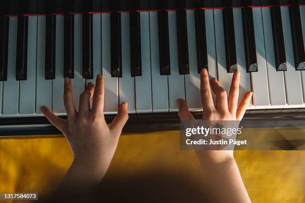 overhead view of a young child playing the piano - piano player ストックフォトと画像