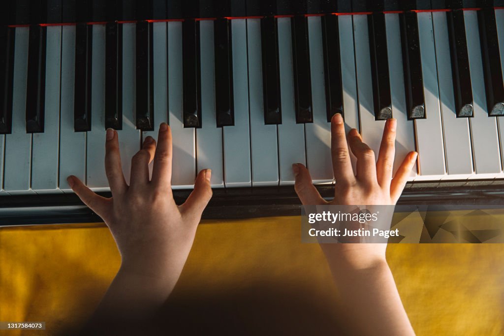 Overhead view of a young child playing the piano