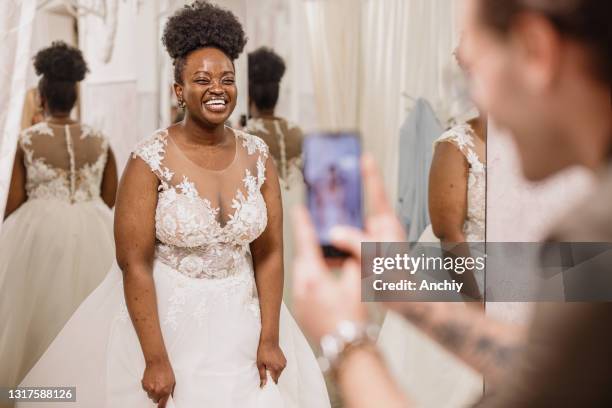 vrienden die foto's van hun mooie vriend nemen die bruids huwelijkskleding draagt - bridal shop stockfoto's en -beelden