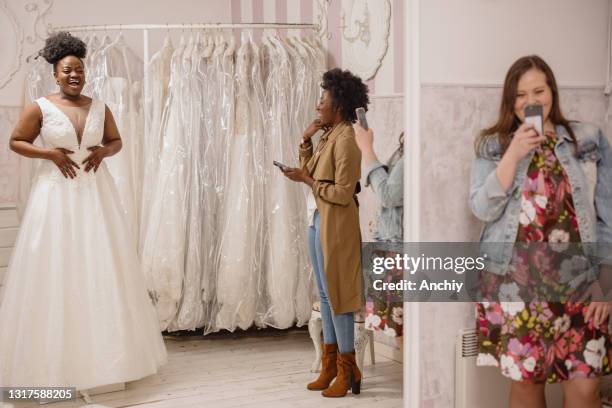 frau versucht, auf hochzeitskleid mit weiblichen freunden spaß und fotografieren. - hochzeitskleid stock-fotos und bilder