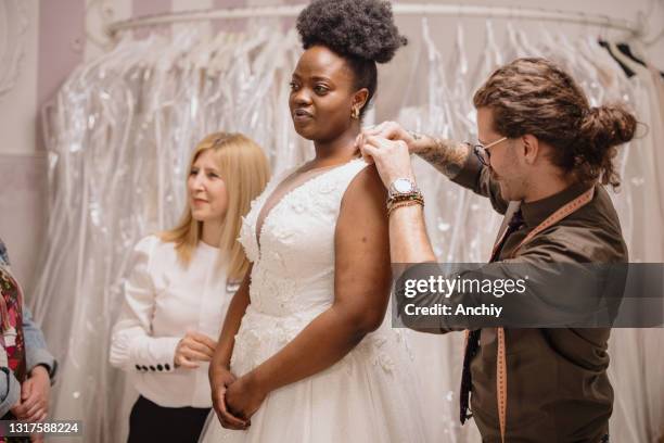 dress designer fitting bridal gown to woman in boutique. - chubby man shopping stock pictures, royalty-free photos & images