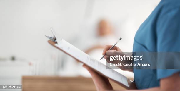 ontsproten van een onherkenbare verpleegster die een patiënten medische grafiek controleert - examination closeup stockfoto's en -beelden