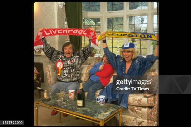 Comedian Faith Brown photographed watching a football match at home with her family, circa 1988.
