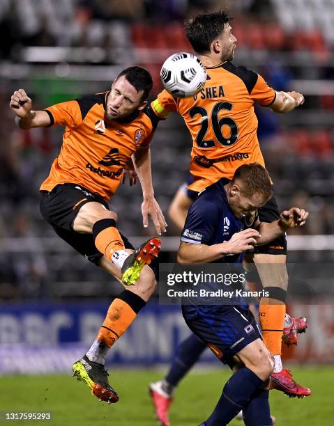 Scott Neville and James O'Shea of the Roar get above Oliver Bozanic of the Mariners as they compete for the ball during the A-League match between...