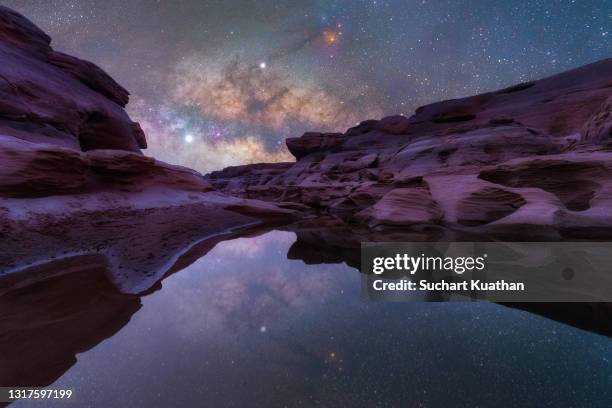 amazing and stunning milky way shining above interesting rock formation with reflections on water at sam pan bok, thailand. - reflection pool - fotografias e filmes do acervo