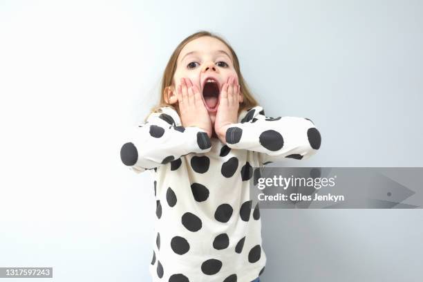 young girl standing in front of blank wall with expressive face - excited child stockfoto's en -beelden