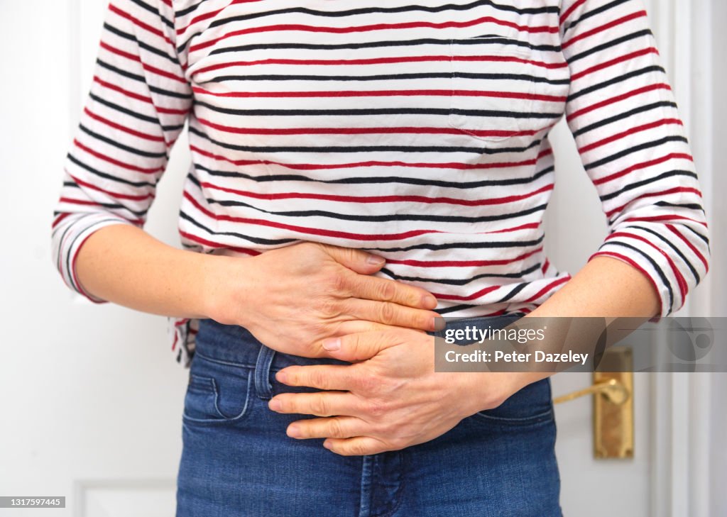 Woman in pain, hands rubbing lower body for relief