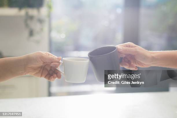 two hands holding cups to toast - マグカップ ストックフォトと画像