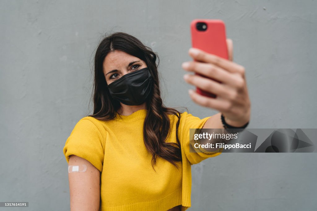 Millennial woman taking a vaxxie just after Covid-19 vaccination - Vaccine selfie