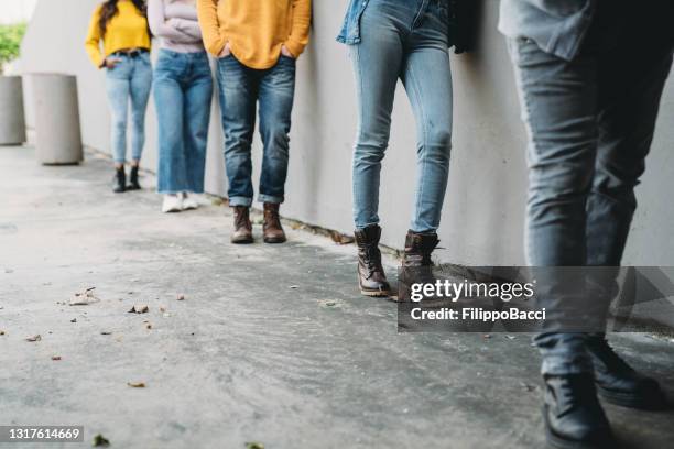 vue basse de section des personnes attendant en ligne devant un magasin - queue photos et images de collection