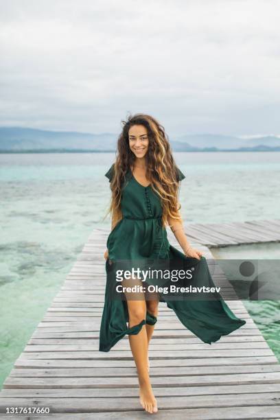 happy laughing woman running by wooden walkway over coral reef on tropical island - teenage girls barefoot stock-fotos und bilder