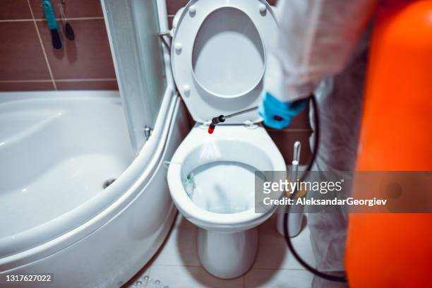 toiletbril sanitaire voorzieningen en desinfectie door medische werkers in hazmat-pakken tegen covid-19 - infection prevention stockfoto's en -beelden