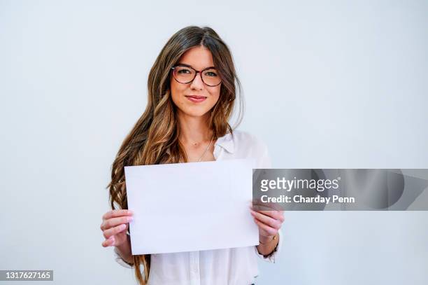 schuss einer attraktiven jungen geschäftsfrau, die allein gegen eine weiße wand steht und ein leeres plakat hält - person holding blank sign stock-fotos und bilder