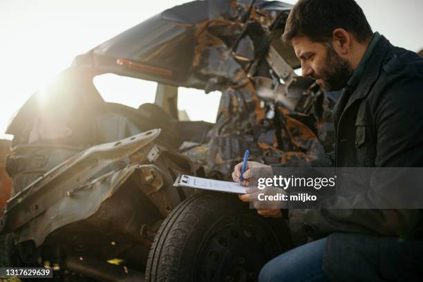 car insurance agent at work by the crashed car - car accident report stock pictures, royalty-free photos & images