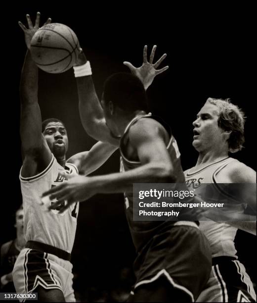 View of American basketball player Magic Johnson , of the Los Angeles Lakers, as he defends against Moses Malone , of the Philadelphia 76ers, during...