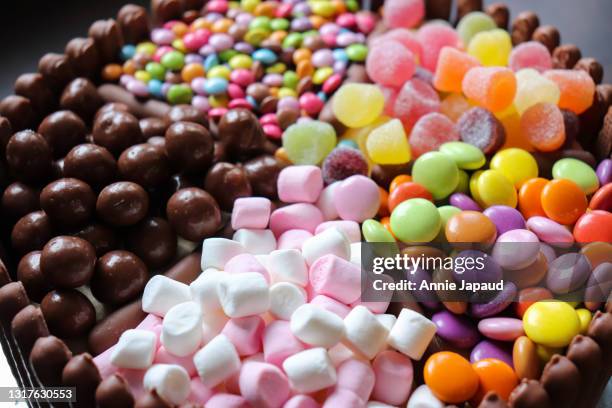 chocolate fingers cake, extreme closeup, piled with smarties, marshmallows and other sweets on top top view - snack background stock pictures, royalty-free photos & images