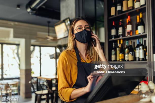 small business owner with face mask keying in check out payment and receiving order - small restaurant stock pictures, royalty-free photos & images