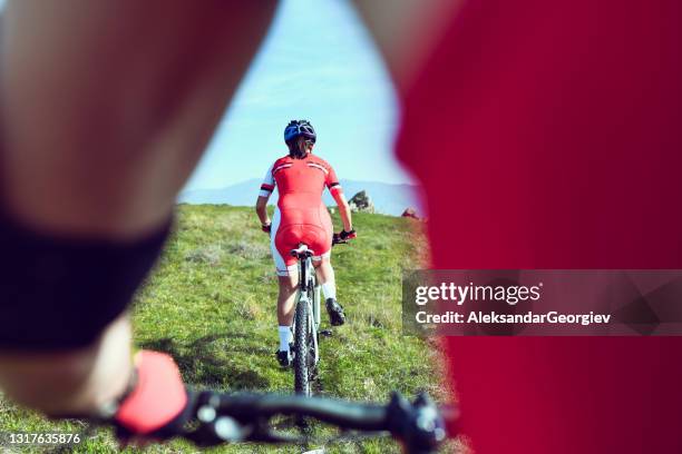 rear view of cyclist couple mountain biking on grass trail - nádega imagens e fotografias de stock