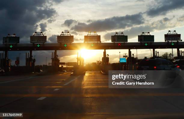 Vehicles drive through a toll plaza on the New Jersey Turnpike as the sun sets on May 11, 2021 in Newark, New Jersey.