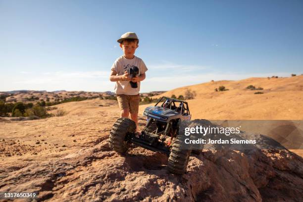 a young boy driving a remote control car on rocky terrain. - remote controlled car stockfoto's en -beelden