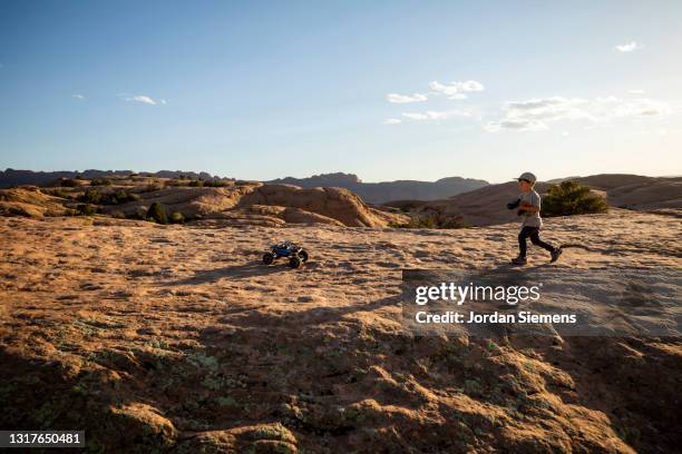 a young boy driving a remote control car on rocky terrain. - remote control car stock pictures, royalty-free photos & images