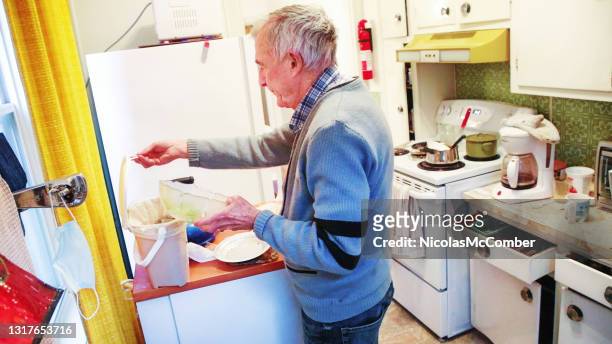 senior man using composting bin in his kitchen while cleaning up - positioned stock pictures, royalty-free photos & images