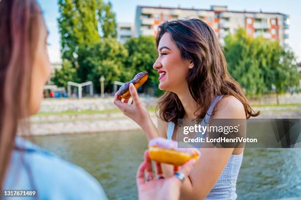 weibliche freunde essen donuts - friends donut stock-fotos und bilder