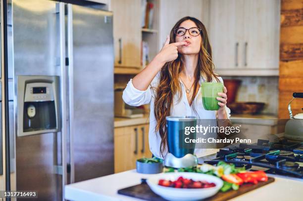 ontsproten van een jonge vrouw die een gezonde smoothie thuis maakt - detox stockfoto's en -beelden