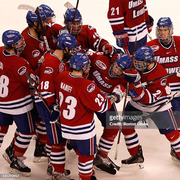 UMass Lowell Riverhawks men's ice hockey team members surround UMass Lowell forward Chris Auger, #16, as they celebrate their 3-2 overtime win over...