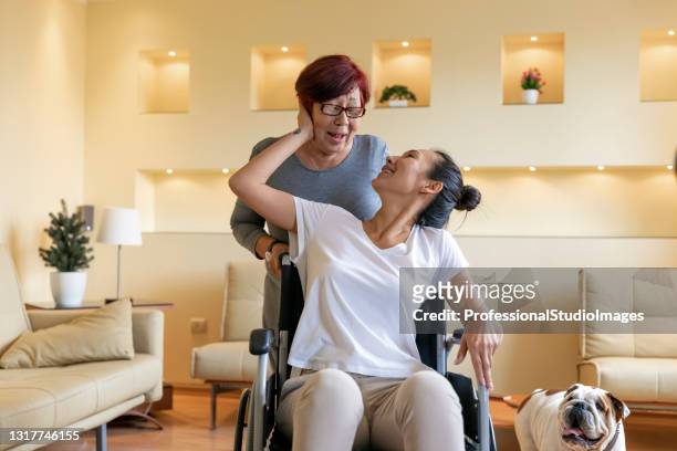 older female physiotherapist is giving a treatment to a mature woman in a wheelchair at home. - disability collection stock pictures, royalty-free photos & images