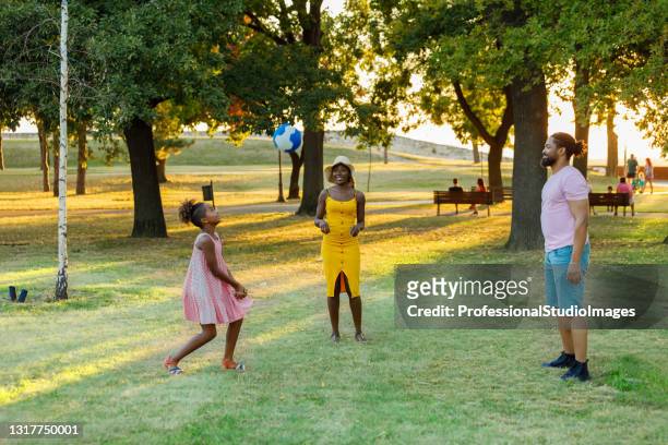 de gelukkige afrikaans-amerikaanse familie speelt volleyball in een park. - volleyball park stockfoto's en -beelden