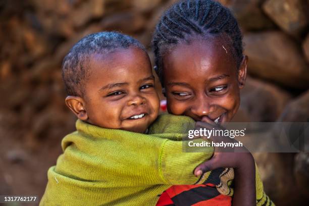 afrikanisches mädchen trägt ihren jüngeren bruder, äthiopien, afrika - äthiopien stock-fotos und bilder