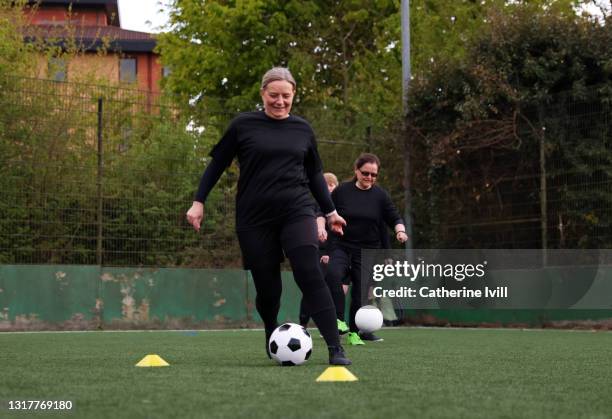 woman dribbles ball during football practice - menopossibilities stock-fotos und bilder