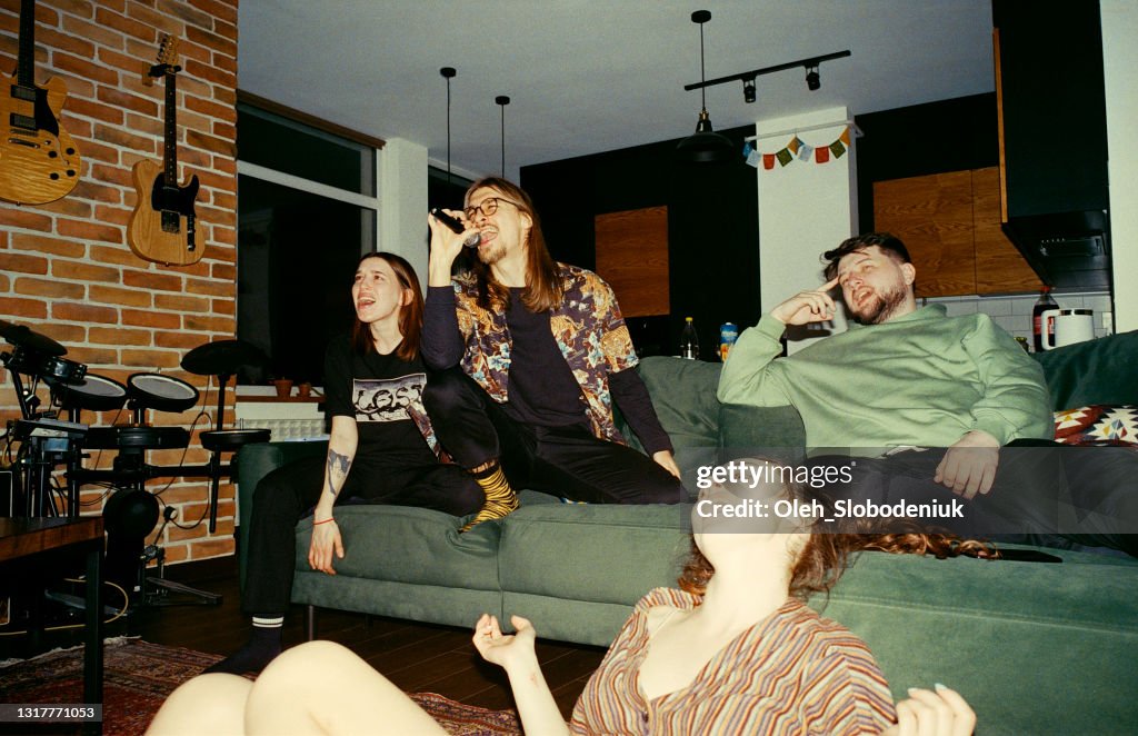 Friends having fun at home. Singing karaoke