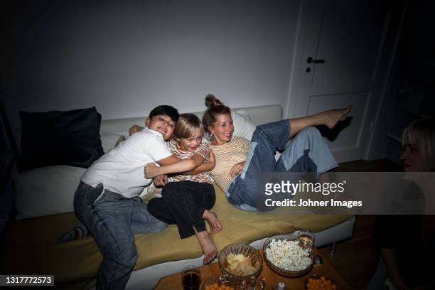 mother with sons relaxing on sofa - movie night stock pictures, royalty-free photos & images
