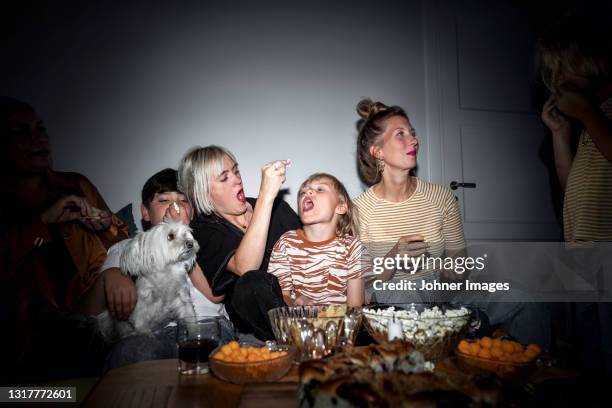 family with kids snacking in living room - movie night stock pictures, royalty-free photos & images