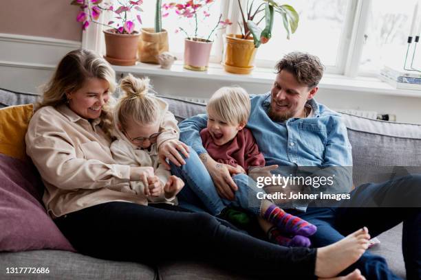 parents with children sitting on sofa - real mother stock pictures, royalty-free photos & images