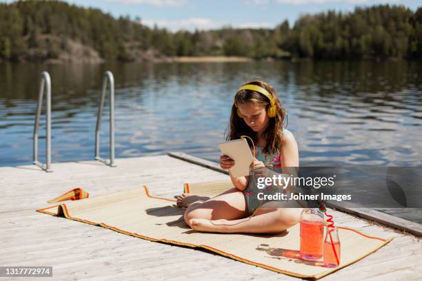 girl using digital tablet on jetty - água parada imagens e fotografias de stock