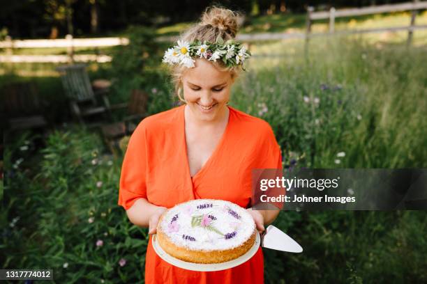 smiling woman holding cake in garden - midsummer sweden stock-fotos und bilder