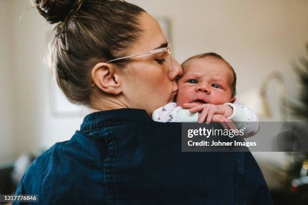 mother kissing baby - vaterschaft stock-fotos und bilder