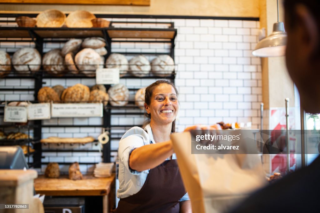 De eigenaar die van de bakkerij voedselpakket aan klant geeft