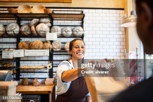 De eigenaar die van de bakkerij voedselpakket aan klant geeft De eigenaar die van de bakkerij voedselpakket aan klant geeft